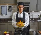 Female chef student making stir fry